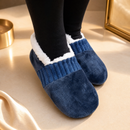 Pés calçando as pantufas de quarto RECANTO azul-marinho com meia preta